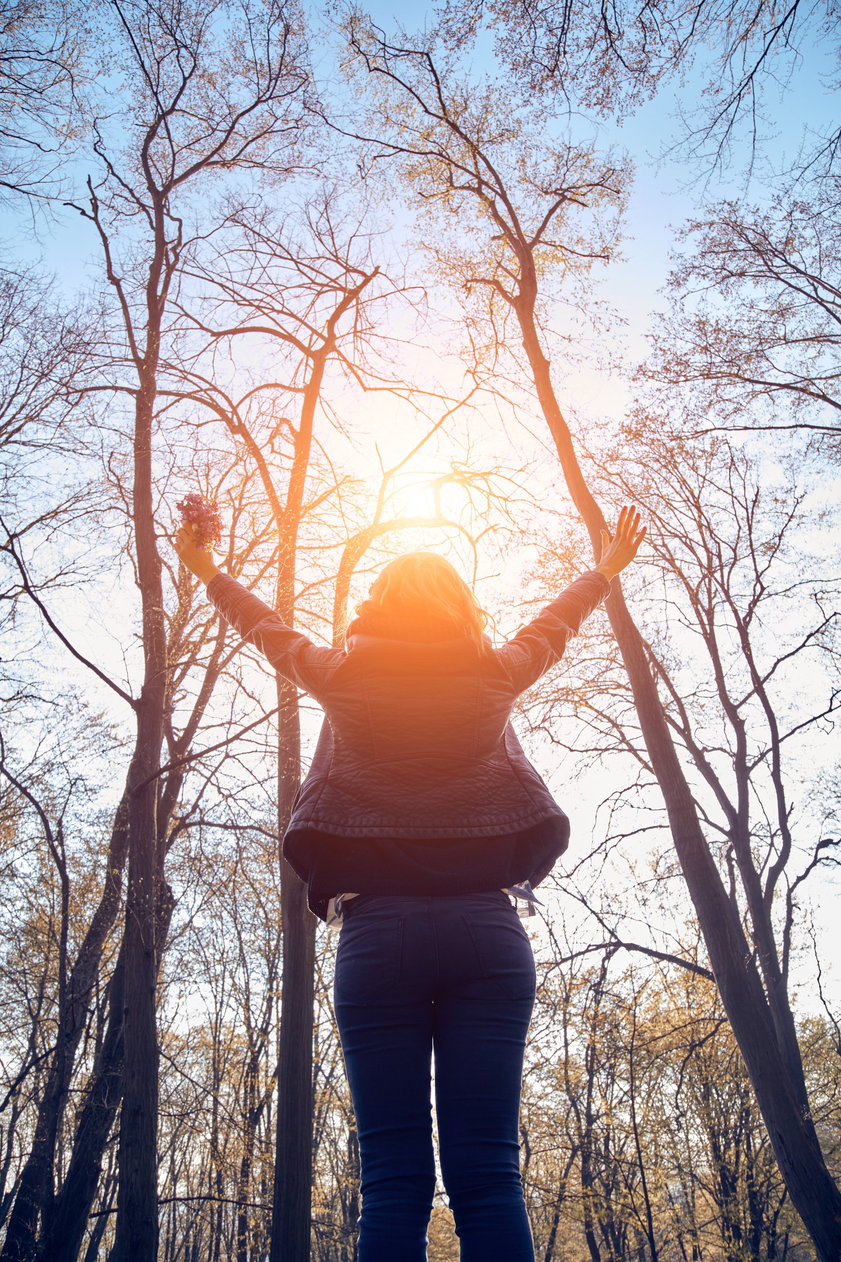 Woman holding flowers with arms wide open.